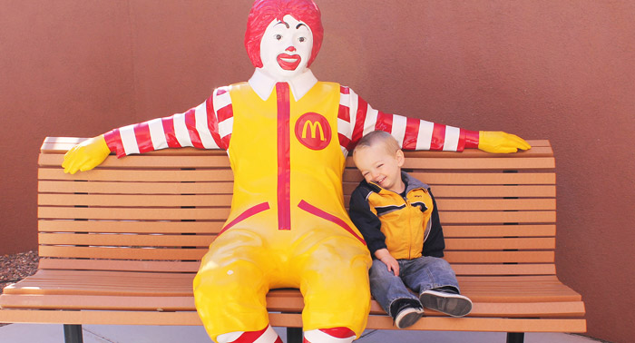 Young little boy Cj sitting with the Ronald McDonald bench outside of the rmhc