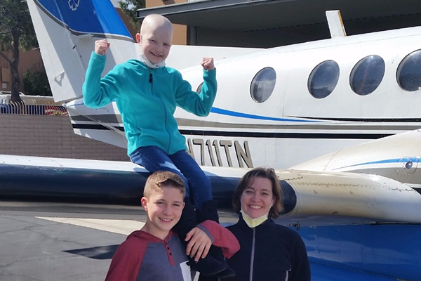 RMHC guest Galia Sodoma sitting on wing of airplane and brother and mother below her on ground